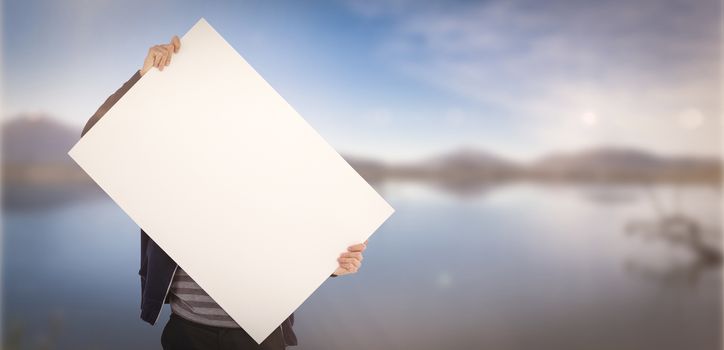 Man holding billboard in front of face against lake