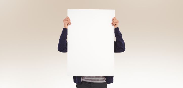Man showing billboard in front of face against beige background