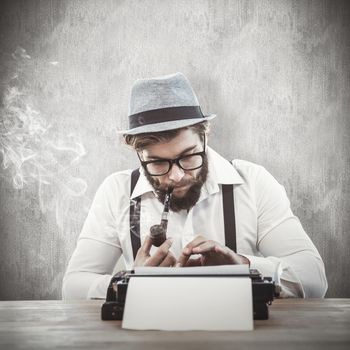 Hipster smoking pipe while working at desk against white and grey background