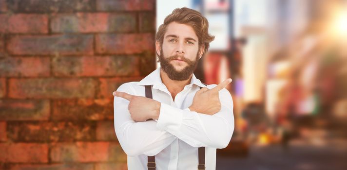 Confident hipster pointing sideways with arms crossed against wall of a house