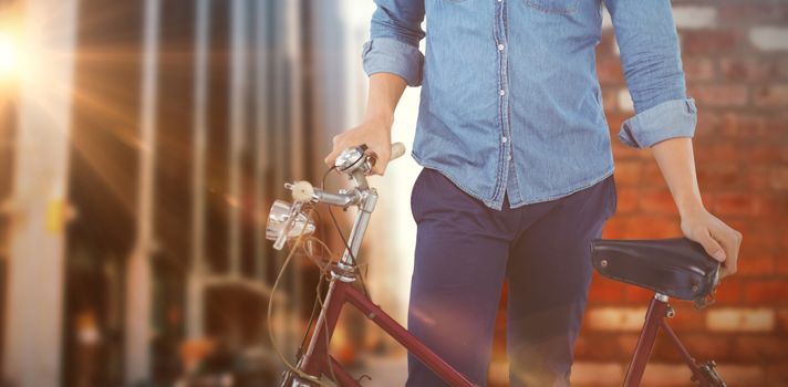 Portrait of hipster wearing knitted hat standing with bicycle against wall of a house