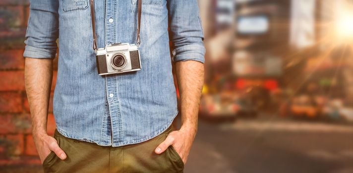 Hipster man holding digital camera against wall of a house