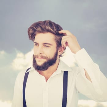 Hipster scratching head while thinking against beautiful blue cloudy sky