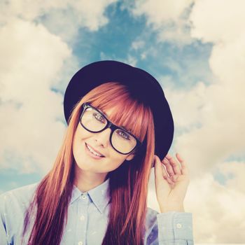 Smiling hipster woman posing face to the camera against blue sky with white clouds