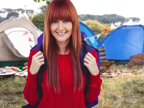 Smiling hipster woman with a travel bag taking selfie against empty campsite at music festival