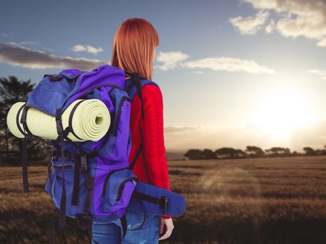 Smiling hipster woman with a travel bag against landscape of the countryside