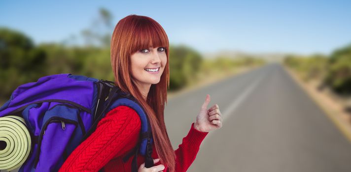 Smiling hipster woman with a travel bag against picture of a street