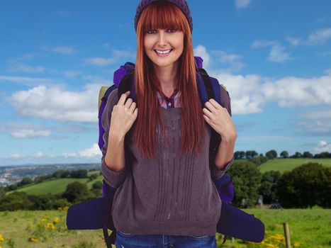 Smiling hipster woman with a travel bag against countryside