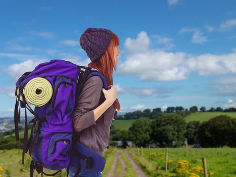 Side view of a hipster woman with a travel bag against countryside