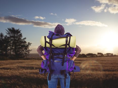 Rear view of a hipster woman with a travel bag against landscape of the countryside