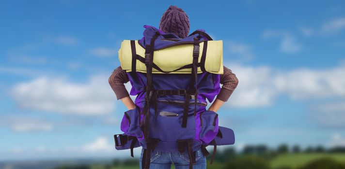Rear view of a hipster woman with a travel bag against countryside