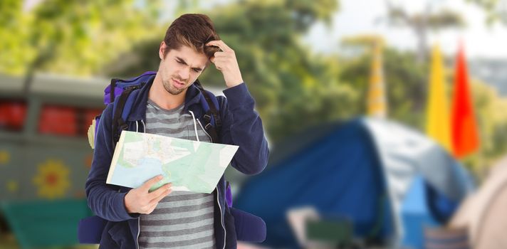 Man scratching head while looking in map against empty campsite at music festival