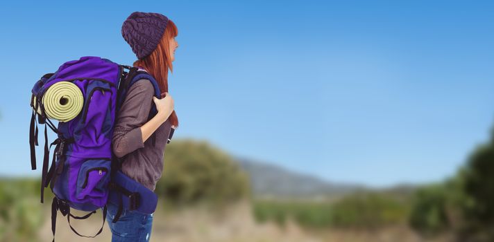 Side view of a hipster woman with a travel bag against mountain trail