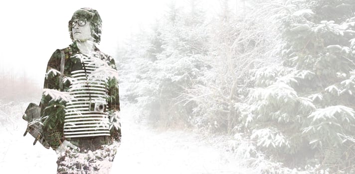 Thoughtful hipster looking away against snow covered road along trees