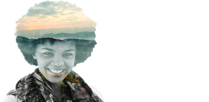 Brunette smiling to the camera against trees and mountain range against cloudy sky