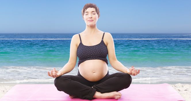 Pregnent woman sitting on mat in lotus pose over white background against waters edge at the beach