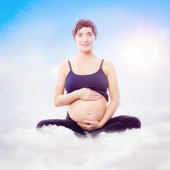 Portrait of happy expecting woman sitting on exercise mat against blue sky with white clouds