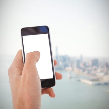 Cropped hand of man using mobile phone against city by the sea