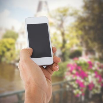 Male hand holding a smartphone against canal in amsterdam