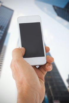 Male hand holding a smartphone against skyscraper