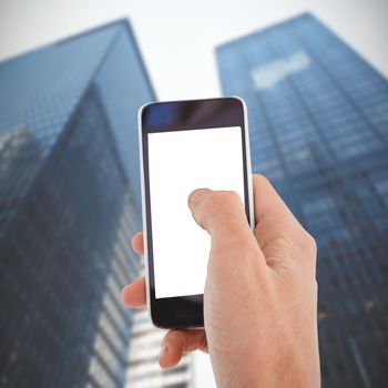 Cropped hand of man using mobile phone against low angle view of skyscrapers