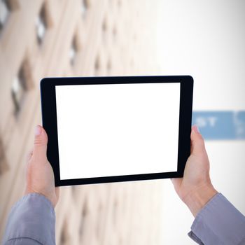 Cropped hand of man holding digital tablet against wall street