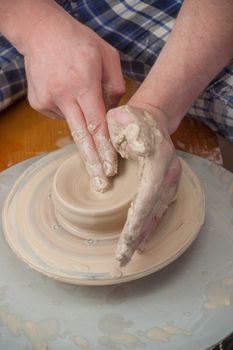 Hands of a potter, creating an earthen jar on the circle