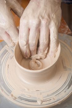 Hands of a potter, creating an earthen jar on the circle