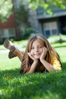 portrait of little girl laying on the grass in summer environment