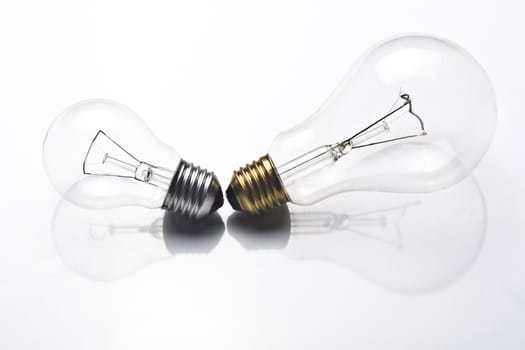 A small light bulb with silver screw and a large one with golden screw on white background