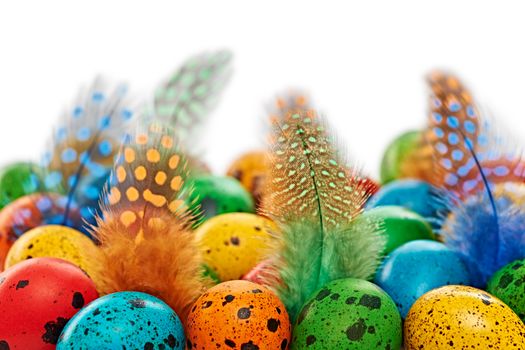 Easter eggs background. Quail eggs hand painted multicolored, and feathers. Close up. Unusual creative holiday greeting card