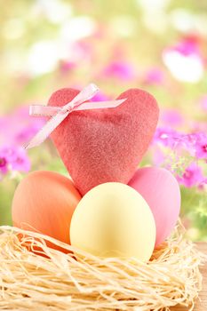 Easter eggs in in straw nest.  Hand painted decorated multicolored eggs and heart on floral background. Unusual creative holiday greeting card 