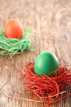 Easter eggs in nests. Hand painted decorated multicolored eggs with bow on wooden background. Unusual creative holiday greeting card 