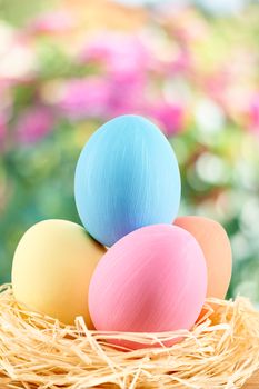 Easter eggs in in straw nest.  Hand painted decorated multicolored eggs on floral background. Unusual creative holiday greeting card 