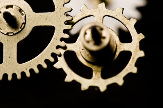 Horizontal macro photography of three golden clock wheels on black background