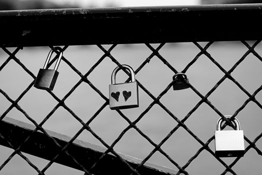 Black and white picture of a metal lock with two hearts written on the front