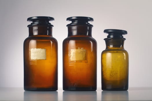 Three old medical brown glass jars isolated on grey  background