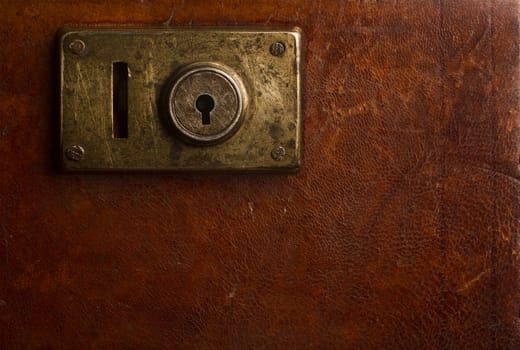 Horizontal close up of an old locking mechanism on a vintage suitcase made of brown leather