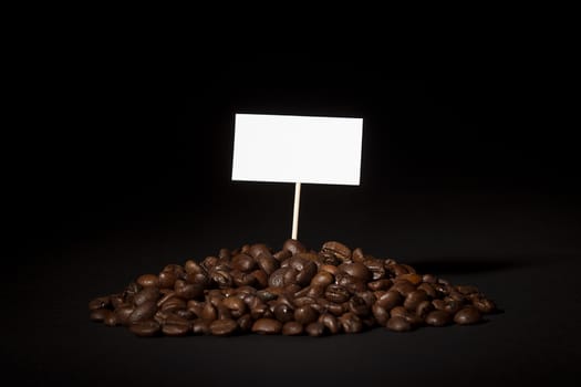 A pile of coffee beans with an empty sign on top of them shot on black background