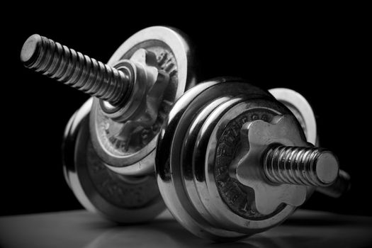 Horizontal close up of a pair of heavily used chrome weights on black background