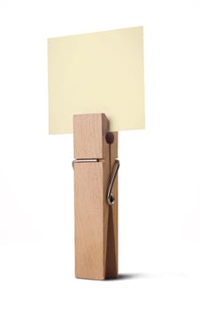 wooden peg holding a yellow note isolated on white background