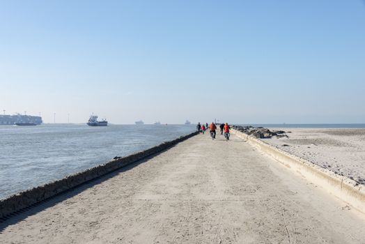 HOEK VAN HOLLAND,NETHERLANDS - FEBRUARI 17: Unidentified people biking on the pier of hoek van holland near the sea on Februari 17 2016 in Hoek van Holland, this beach is the beach with the view on inccoming ships to Rotterdam harbour.