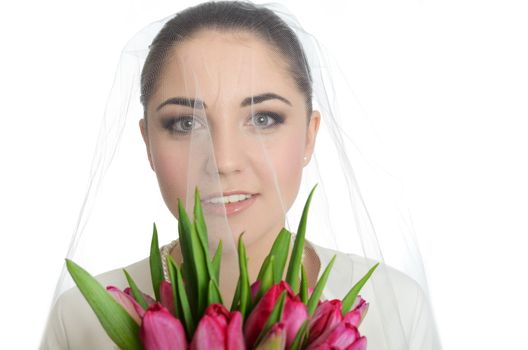 Female model, face covered with veil. Bride holds tulips bouquet. Portrait in studio with white background.

