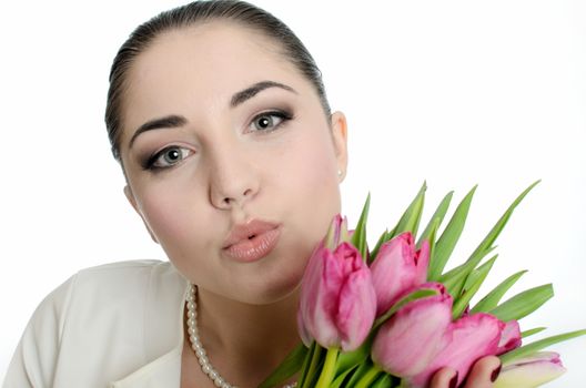 Young bride sending a kiss. Female model with white veil, pearls and tulips bouquet. 