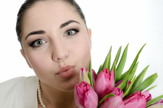 Young bride sending a kiss. Female model with white veil, pearls and tulips bouquet. 