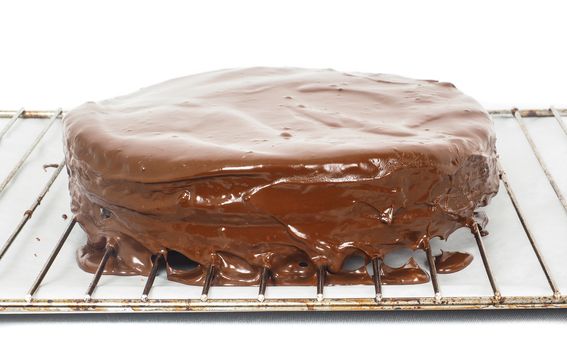 Chocolate icing dripping off from freshly made sacher torte cake