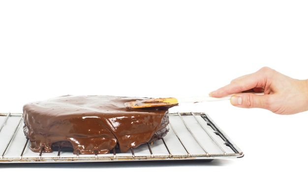 Pastry chef making final touches to a sacher chocolate cake with icing