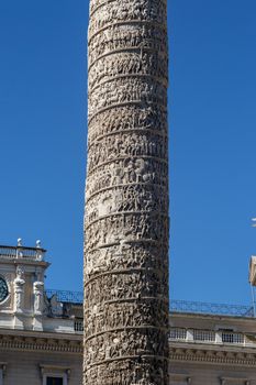 Close up detailed view of Column of Marcus Aurelius with historical hieroglyphics at Piazza Colonna, on bright blue sky background.