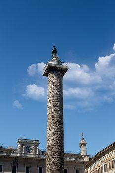 Close up detailed view of Column of Marcus Aurelius with historical hieroglyphics at Piazza Colonna, on cloudy blue sky background.