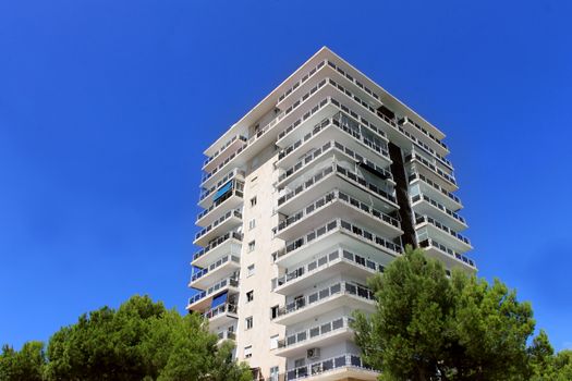Exterior of a tall modern apartment building with blue sky background.
